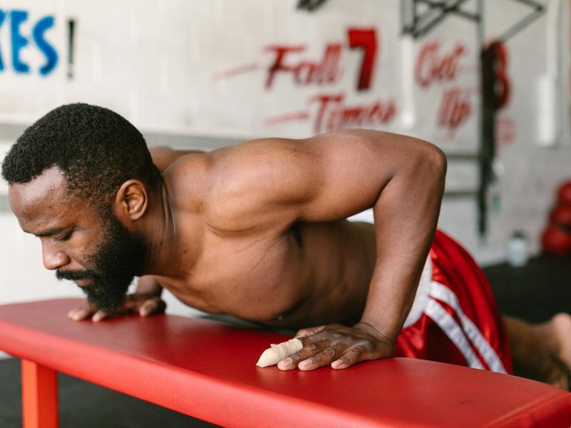Man in a focused stance performing a bodyweight exercise in a minimalist room.